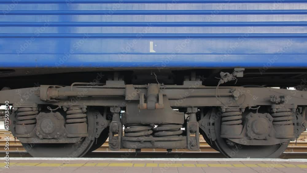 Wheels of the train car old rusty suspension blue wagon standing at the railway station closeup Wheels of the train car old rusty suspension blue wagon standing at the railway station closeup