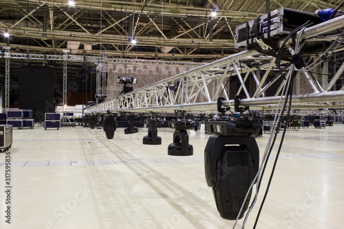 Installation of professional sound, light, video and stage equipment for a concert. Stage lighting equipment is clamped on a truss for lifting.