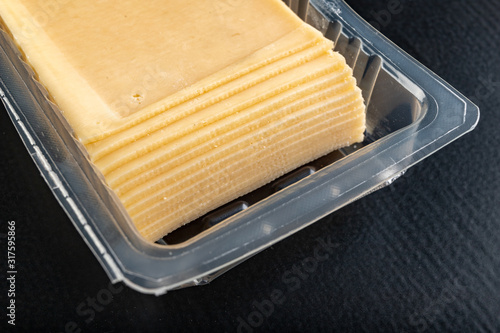 Slices of yellow cheese in a plastic package. Food from the market on the kitchen table.
