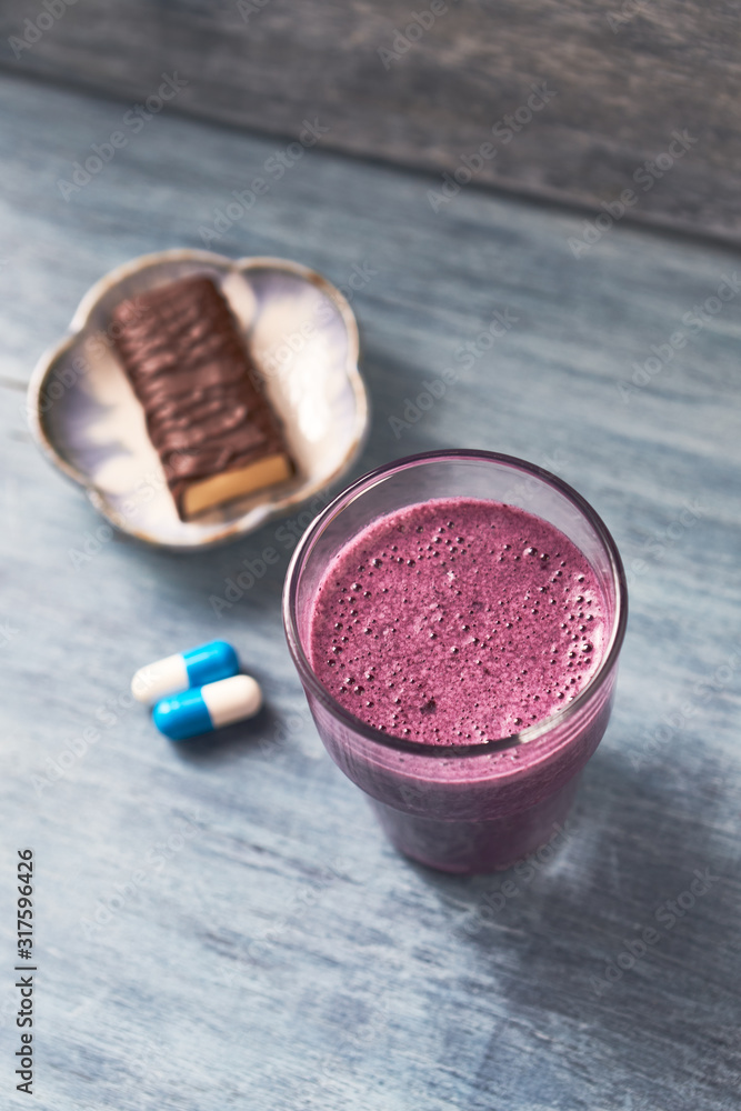 Glass of Protein Shake with milk and blueberries, Creatine capsules and Protein bar. Concept for Sport nutrition. Rustic wooden background. Copy space. Glass of Protein Shake with milk and blueberries, Creatine capsules and Protein bar. Concept for Sport nutrition. Rustic wooden background. Copy space.