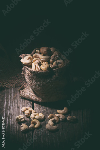 Cashew nuts in a bag on a wooden, rustic , dark background.