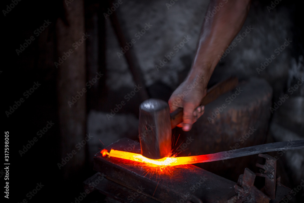 Blacksmith's hands at work. In one hand a hammer, in the other a