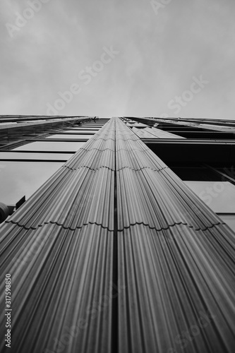 Cuadro en lienzo Low angle greyscale of a modern skyscraper under the cloudy sky