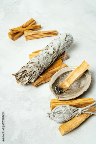 Smudge kit for spiritual practices with natural elements: Palo Santo sticks, dried white sage, Guinea Fowl feather, crystals, sea pearl shell Abalone on a light background. Balancing the soul. photo