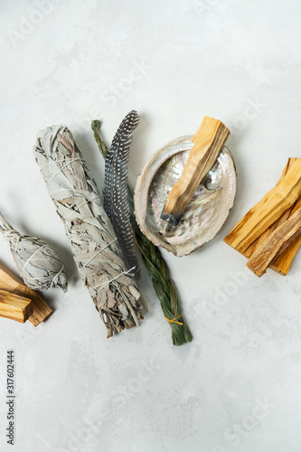 Smudge kit for spiritual practices with natural elements: Palo Santo sticks, dried white sage, Guinea Fowl feather, crystals, sea pearl shell Abalone on a light background. Balancing the soul. photo