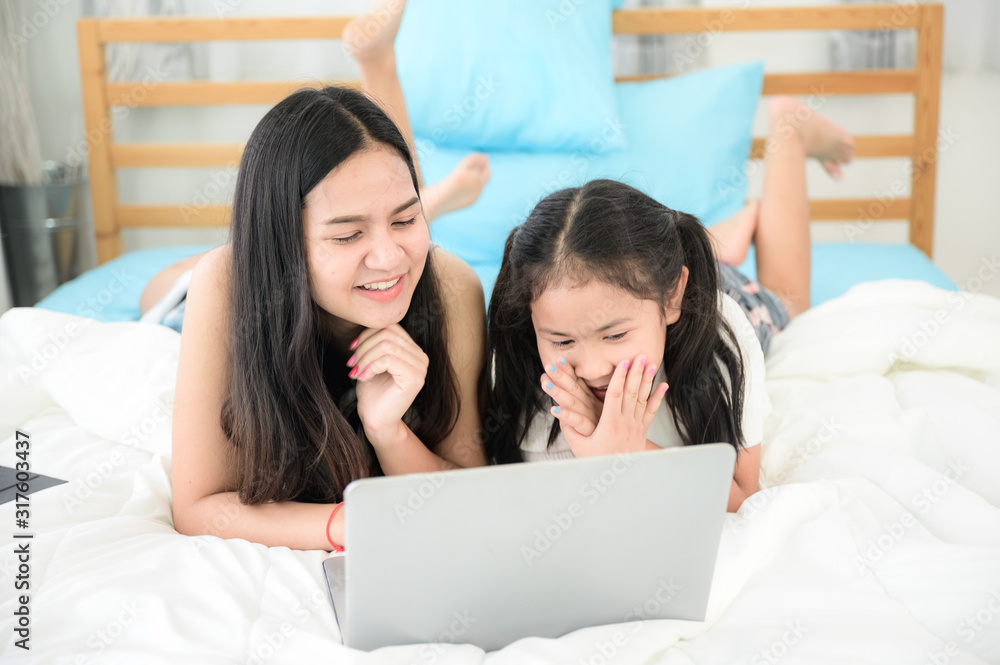 2 sisters are happily using their tablet on their beds. 2 sisters are happily using their tablet on their beds.