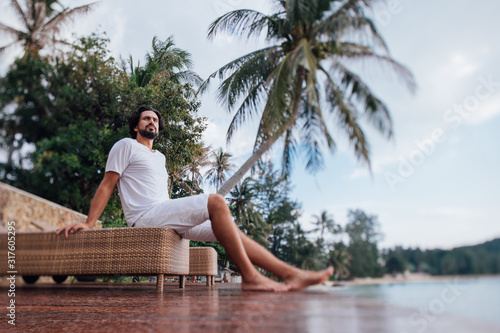 A man on the terrace of a house on the tropical coast by the sea