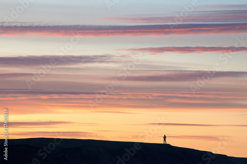 Man stands on a mountain at sunset
