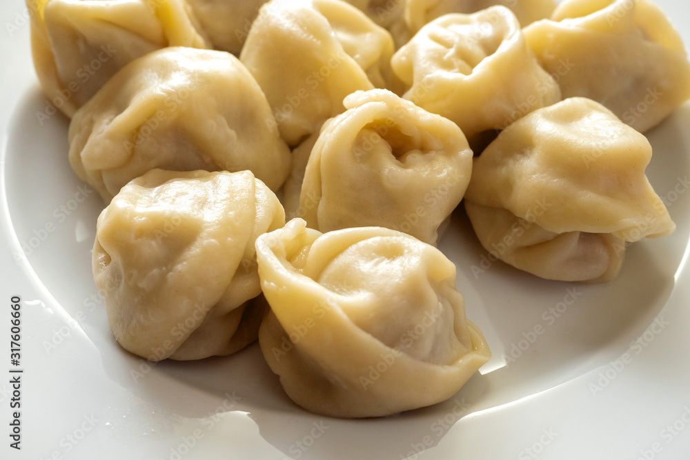 Portion of traditional Russian cooked dumplings on a white plate and wooden table, Close up. Portion of traditional Russian cooked dumplings on a white plate and wooden table, Close up.