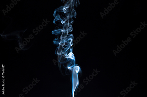 Puff of smoke from an incense stick on a dark background.