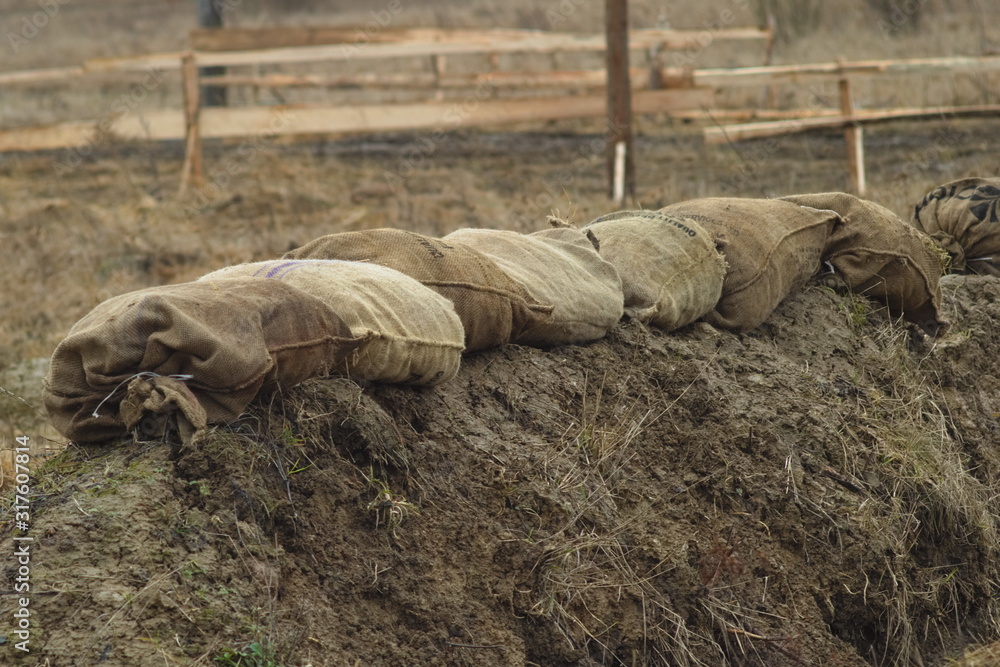 Obraz premium Sandbags made from coarse fabric reinforce the edge of the army trench in the field. Preparing infantry positions during exercises.