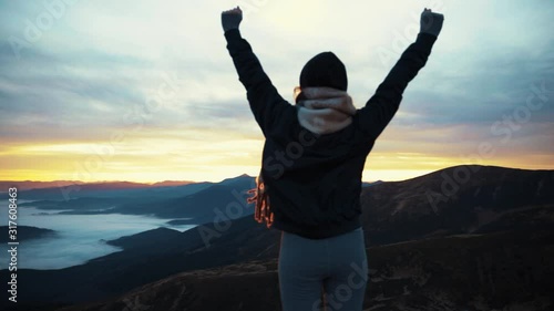 View of camera is approaching zooming woman stands on mountain top rised his hands pure nature enjoying the landscape slow motion sky clouds on the hill outdoor sunrise tourist journay photo