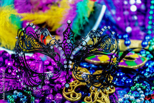 Mardi Gras elegant black metal lace mask against brightly colored beads and feathers - Beautiful background