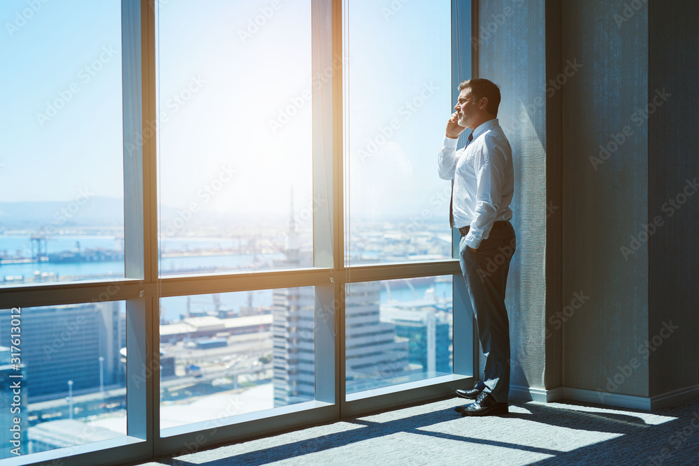 Mature business executive in top floor office space on phone Mature business executive in top floor office space on phone