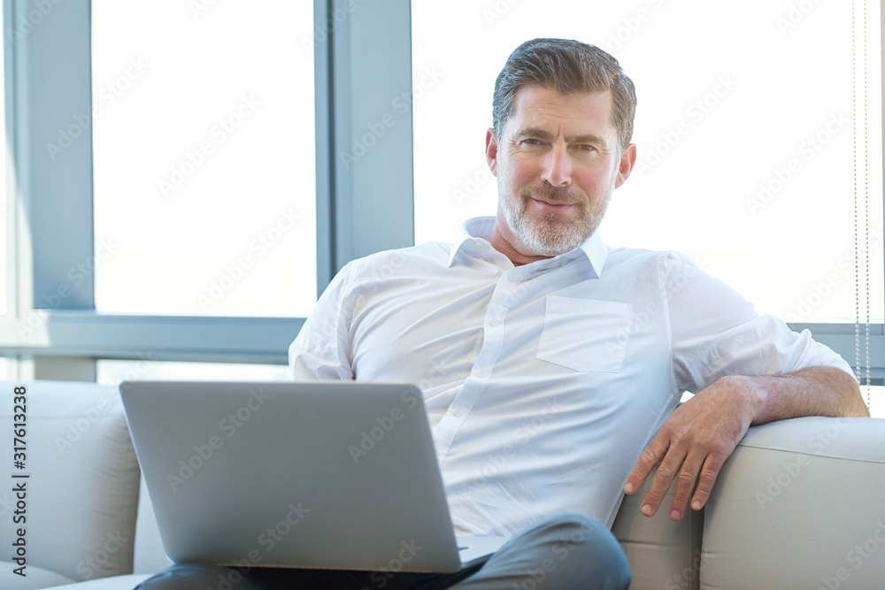 Mature businessman sitting on a couch with laptop Mature businessman sitting on a couch with laptop