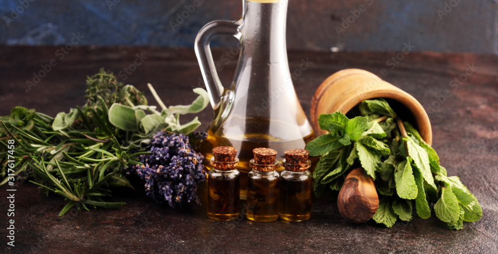 Fresh herbs from the garden and the different types of oils for massage and aromatherapy on table with lavender Fresh herbs from the garden and the different types of oils for massage and aromatherapy on table with lavender