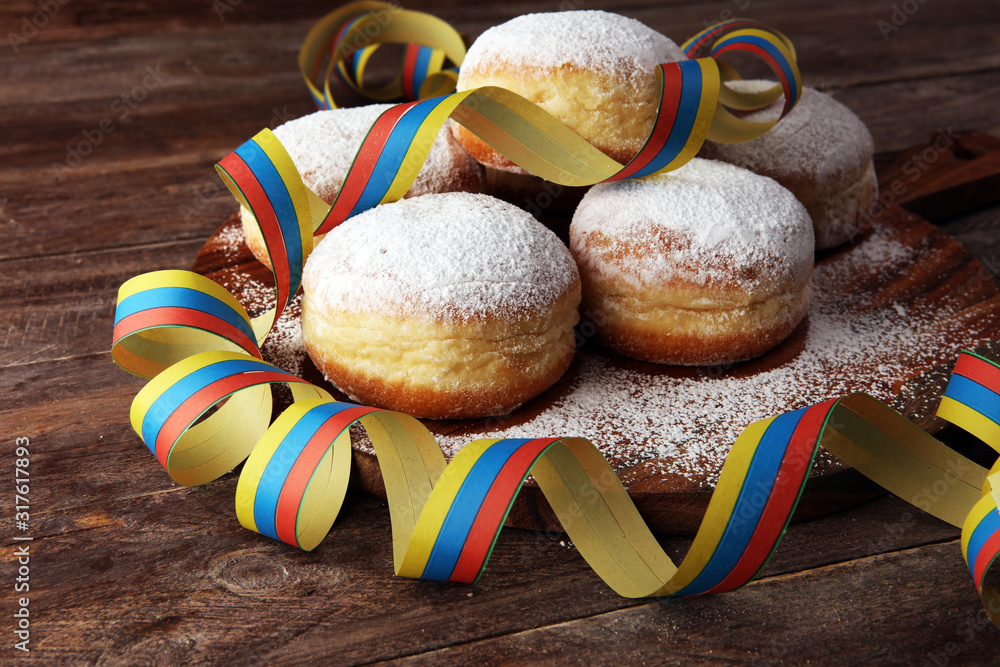 Naklejka premium Carnival powdered sugar raised donuts with paper streamers. German berliner or krapfen for carnival