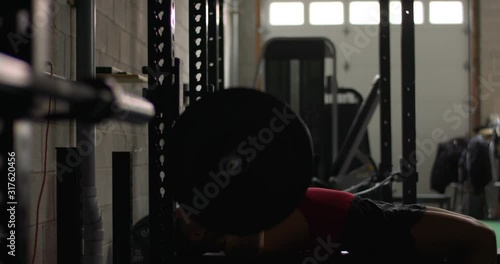 fit asian male benchpress at gym with camera dolly move photo