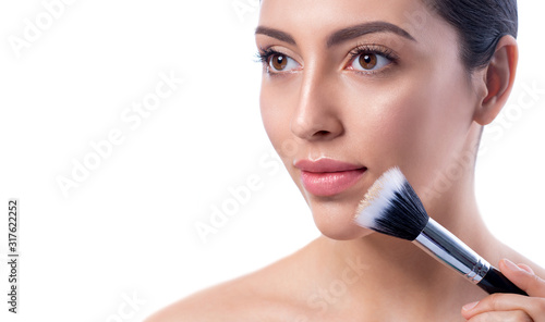 Beautiful girl with cosmetic powder brush for make up.