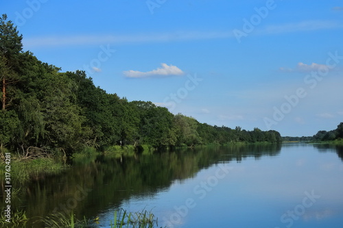 Big beautiful river  blue sky in summer  forested banks against the blue sky. European Sunny summer. Rest on the river Bank in a tent.