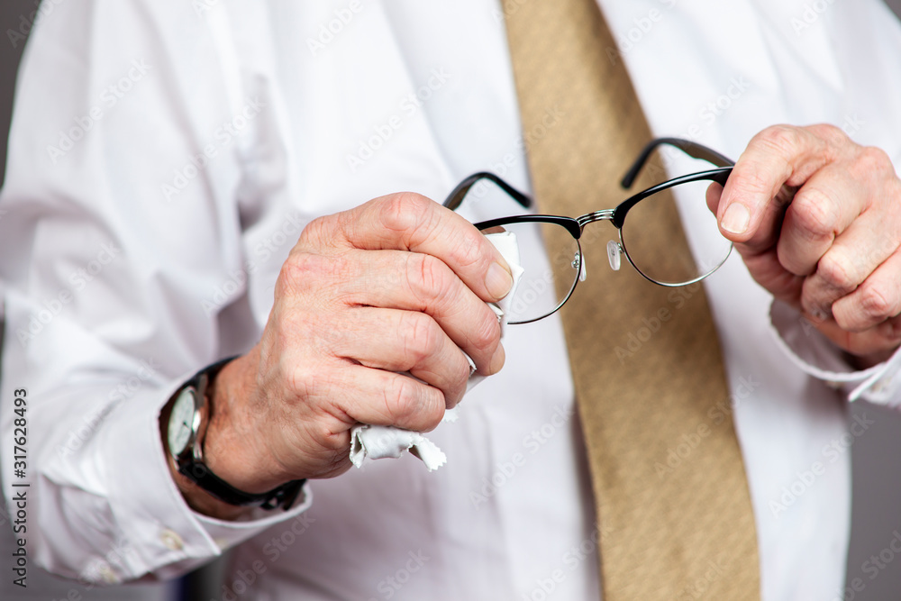 Man in white shirt and gold neck tie cleaning his spectacles Man in white shirt and gold neck tie cleaning his spectacles