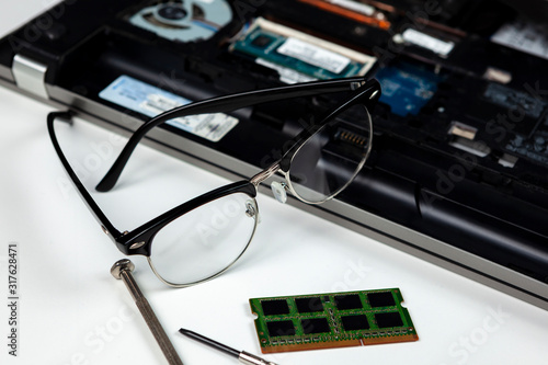 IT engineers spectacles laying on a laptop he is repairing photo