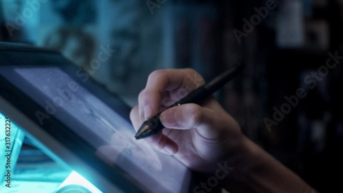 Young artist drawing illustration on tablet, slow motion, shallow depth of field photo