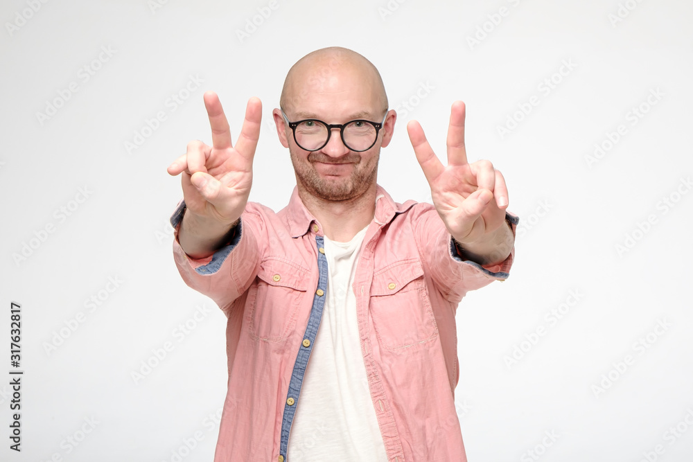 Satisfied, smiling man makes a V-sign with fingers, on two hands, looks at  the camera with a funny expression on face. Stock Photo | Adobe Stock