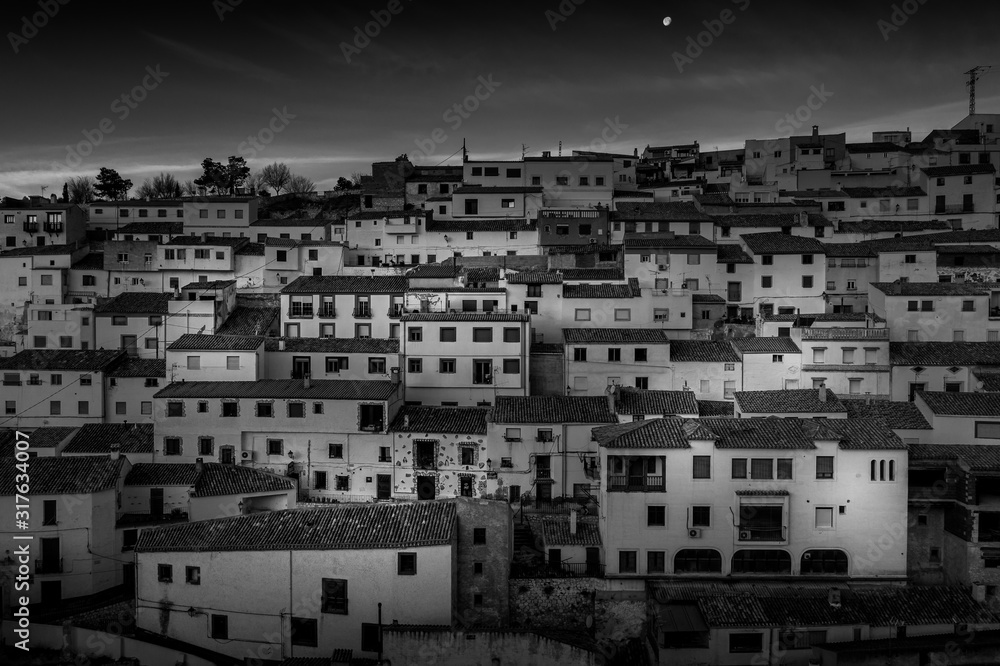 Black and white image of colorful houses with square windows and traditional roofs in Alcala del Jucar Spain