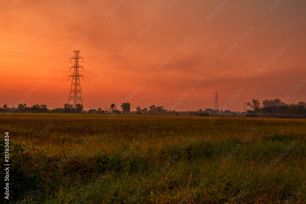 Blurred twilight evening background on rice paddies, with high voltage electricity towers passing through, cool and fresh air while traveling
