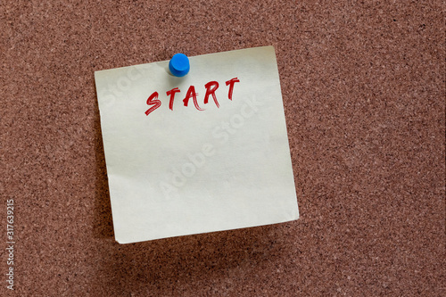 word start at the top of a yellow post it note pinned to cork board with blue thumb tack