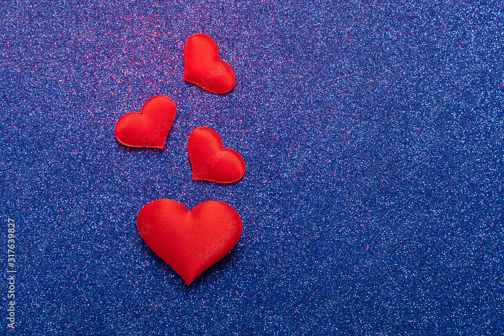 Obraz premium Red hearts symbol of love on a shiny blue background. Valentines day concept. Horizontal frame copy space.