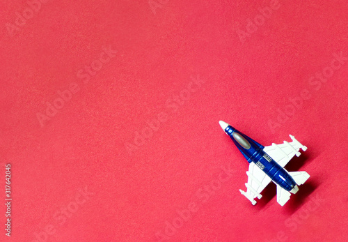 Airplane top view on red background with copy space. The concept of travel and a demonstration flight. Fighter. Military aircraft. A toy.