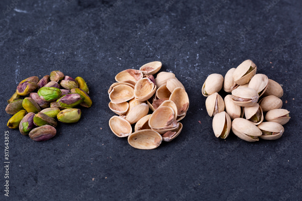 Pistachios (shelled, shells and whole) on slate Pistachios (shelled, shells and whole) on slate