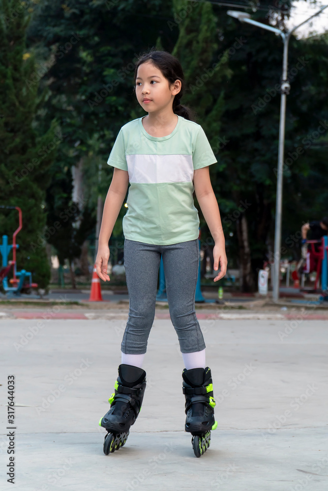 Young asian girl roller skates outdoor in the park. Young asian girl roller skates outdoor in the park.