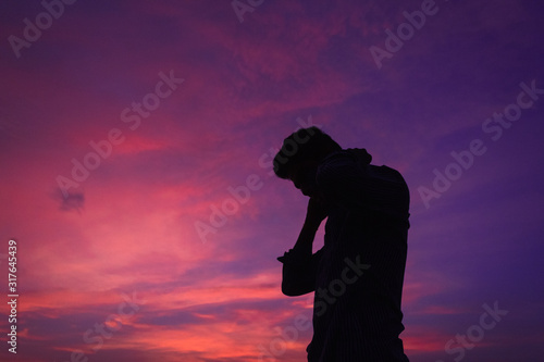 Silhouette of man standing in front of the dramatic cloudy sky during the sunset