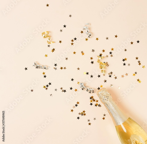 Champagne bottle, confetti stars, holiday and party decoration on beige  back...