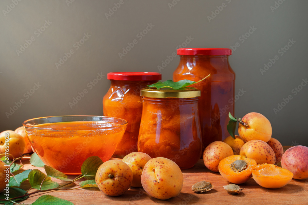 Apricot jam in a glass dish and jars. Fresh ripe apricots with leaves on the table. Homemade confiture. Apricot jam in a glass dish and jars. Fresh ripe apricots with leaves on the table. Homemade confiture.
