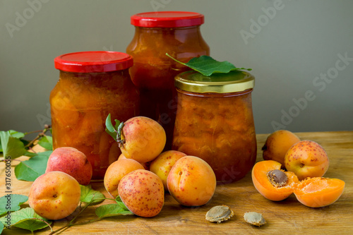 Apricot jam in glass jars and fresh ripe apricots