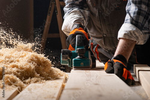 Carpenter works with electrical planer photo