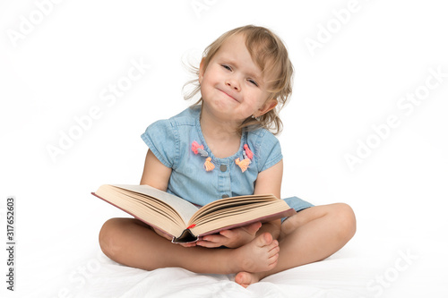 Cute little child in blue dress reading a book