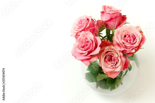 Beautiful pink roses in a vase top view on white table with copy space. Home interiour. Pastel colors