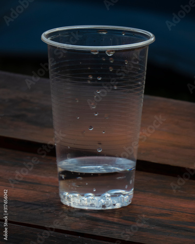 Vaso plástico sobre mesa de madera con fondo azul