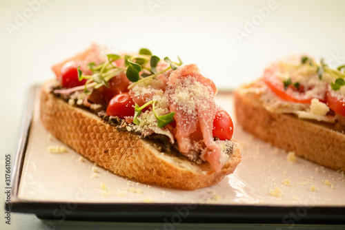 Traditional Italian bruschetta with parmesan cheese, tomato, prosciutto meat, mushrooms, seasoned with herbs