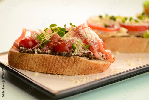 Traditional Italian bruschetta with parmesan cheese, tomato, prosciutto meat, mushrooms, seasoned with herbs