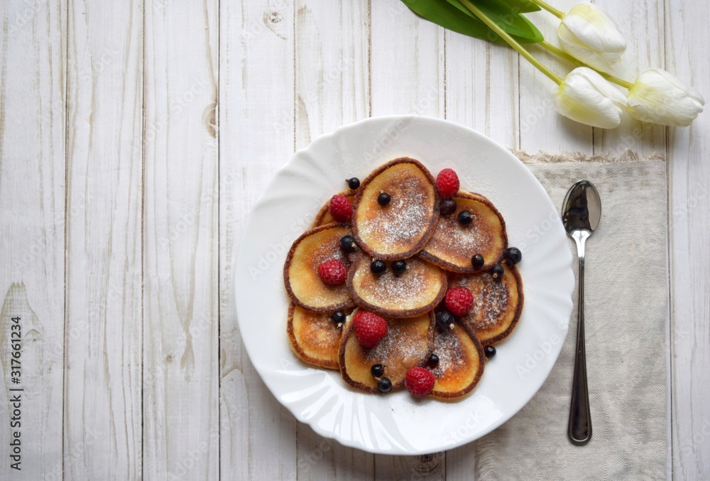  Top view pancakes with berries in a white plate on a white wooden background