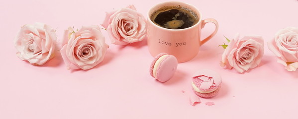 Valentine's day background banner . Pink cup of coffee, pink roses and pink macaroons on pink background. Romantic backdrop. Copy space