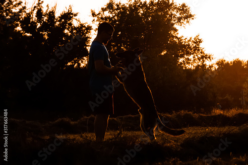 View on a man and german shepherd dog during a sunset