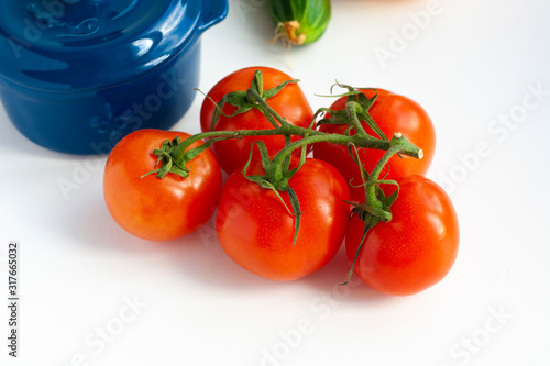 Ripe tomatoes on a branch and blue cooking pot