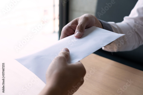 The businessman receiving bribe money in a white envelope form another man at the office